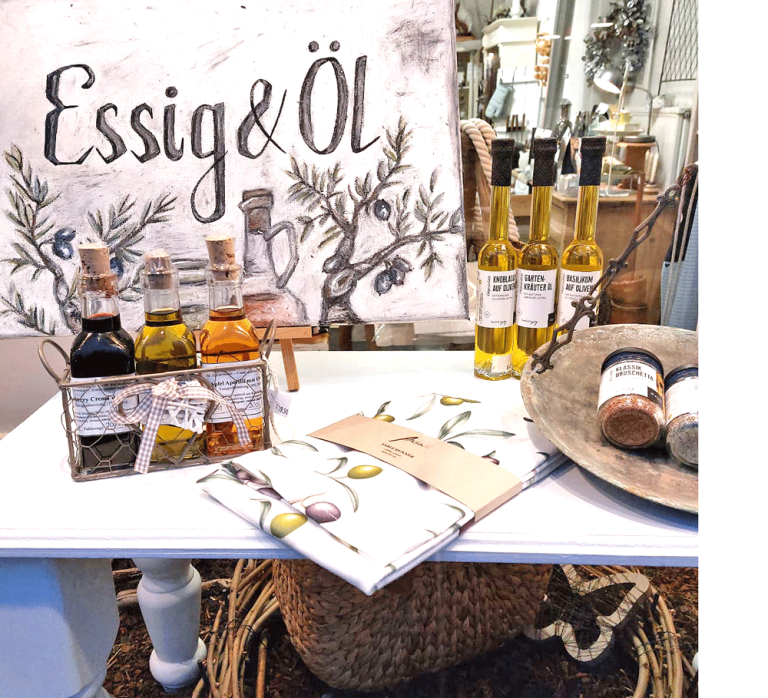 Essig Verschiedene Sorten Essig integriert in harmonischer Schaufensterdekoration, mit Holz- und Kunstelementen kombiniert